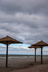 Straw umbrellas from the sun at sea. Cloudy weather and stormy sea.