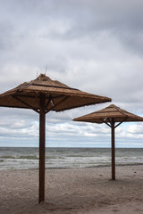 Straw umbrellas from the sun at sea. Cloudy weather and stormy sea.