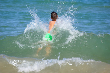 Happy little boy run play with waves on beach of Mediterranean