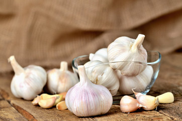 Garlic cloves and bulbs in glass places on rustic wooden boards