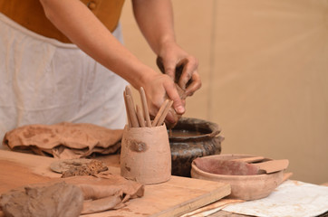 Hand of medieval craftsman female potter preparing clay - moistens and kneads the clay before work