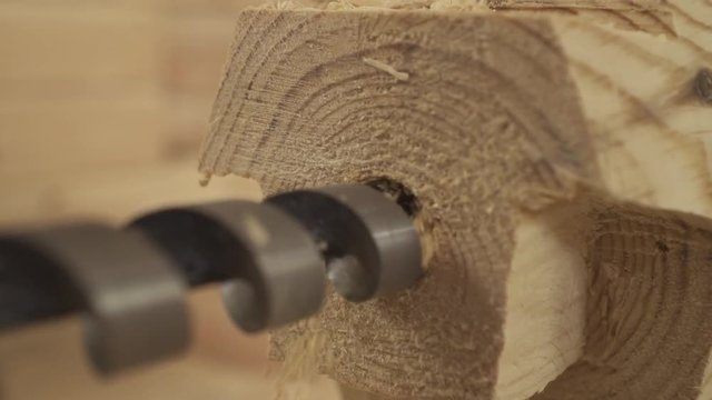 drill a hole in a wooden bar close-up shavings