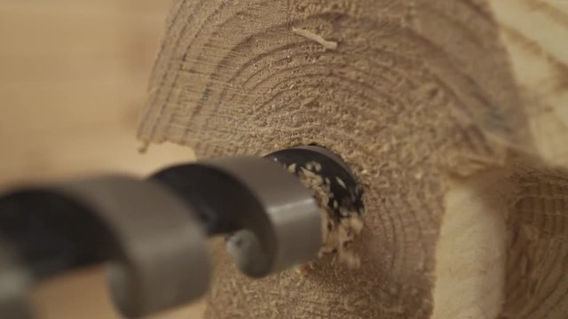 drill a hole in a wooden bar close-up shavings