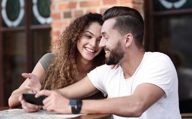 Fototapeta premium Happy loving couple using a smartphone sitting in terrace