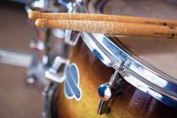 Pair of drumsticks lying on tom-tom drum.