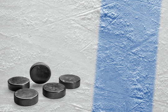 Hockey pucks and a fragment of the ice arena with a blue line