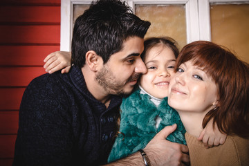 Obraz premium Happy family together. The parents father and mother near red wall and decoration for Christmas