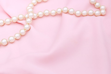 Pearl necklace on the pink fabric with copy space.