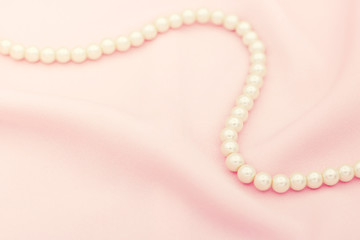 Pearl necklace on the pink fabric with copy space.