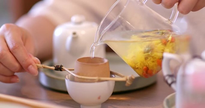 Pouring herbal tea into cup at restaurant