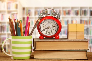 Composite image of alarm clock and books by colored pencils in