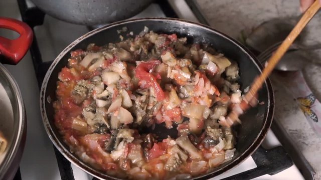 Cook mixes fried vegetables in a frying pan close-up