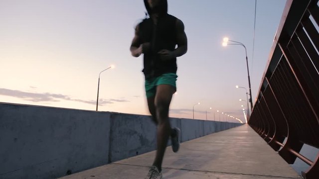 Man jogging on a bridge in city at evening