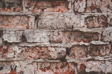 Texture of aged red brick wall painted white color with cracked weathered structure close-up