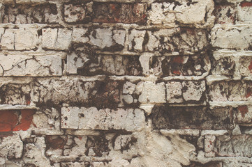 Texture of aged red brick wall painted white color with cracked weathered structure close-up
