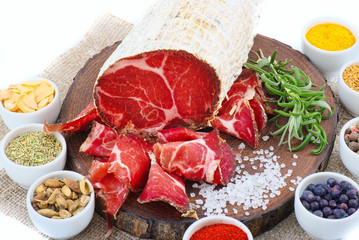 Sliced cured coppa with a sprig of rosemary.