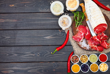 Sliced cured coppa with spices and a sprig of rosemary.