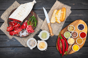 Sliced cured coppa with spices and a sprig of rosemary.
