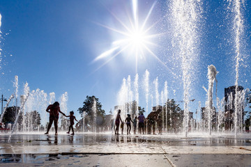 Unidentified Kids playing in the fountain in city park - obrazy, fototapety, plakaty