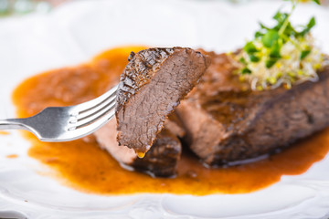 Sliced rare grilled Beef steak Ribeye with sauce on white plate. Selective focus