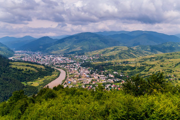Fototapeta premium Thick and dense clouds in the sky floating above the mountains and the town below
