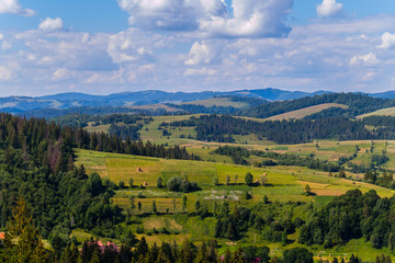 Fototapeta premium Mountain plots and colorful fields against a blue sky with white clouds