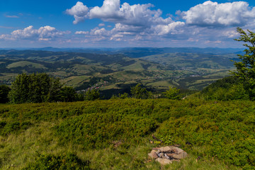 Naklejka premium The green playground is overgrown with thick lush grass with a beautiful view of the distance to the picturesque valleys and houses stretching between them stretching out with a long white thread.