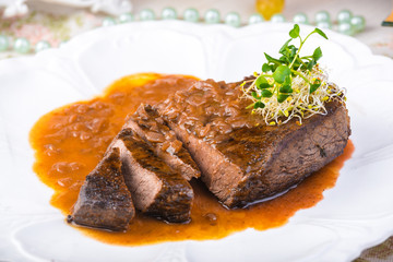 Well-done grilled marinated beef flank steak with sauce on plate