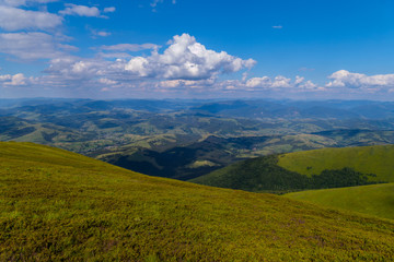 The green grassy top of the mountain with a beautiful view around for many kilometers up to the horizon line.