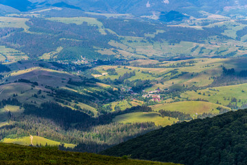 Obraz premium A small authentic rural village at the foot of a mountain range with tall trees