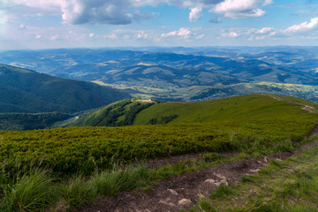 Mountain road leading to the descent of a high hill against the blue sky