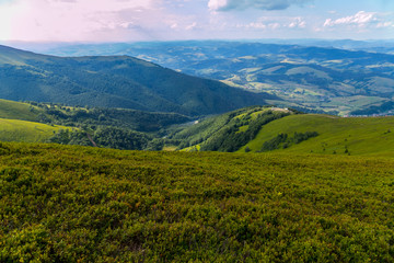 Green mountain valley with small depressions against the background of the endless blue sky