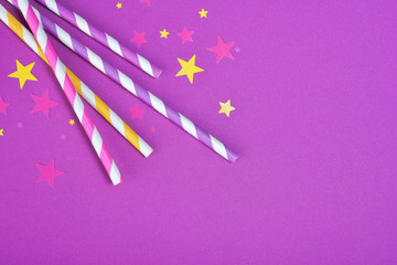 Colorful cocktail straws with confetti in the shape of stars as attributes of party