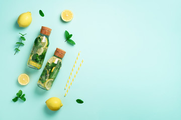 Bottle of detox water with mint, lemon on blue background. Flat lay. Citrus lemonade. Summer fruit infused water. Top view with copy space.