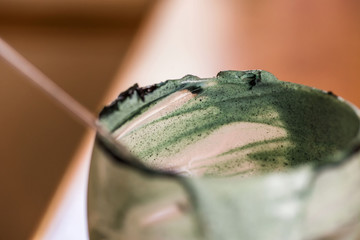 Closeup view emptied glass of fresh kefir probiotik drink mixed with green spirulina powder with spoon inside on kitchen table