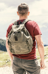 Junger Mann mit Wanderrucksack blickt in die Ferne