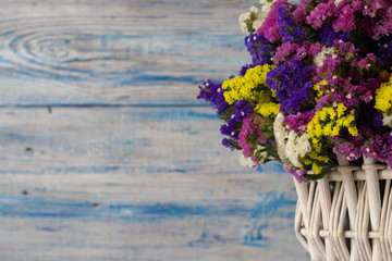 white wicker basket with multi-colored wildflowers. blue and white wooden background