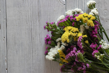 Fototapeta na wymiar bouquet of colored wildflowers on white / blue background