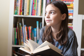beautiful girl reads a dark book on the background of a bookcase