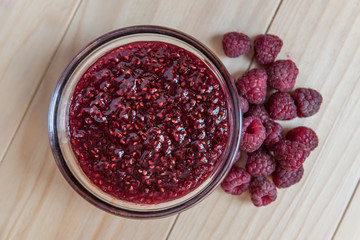 Homemade Raspberry jam in a glass bowl with fresh ripe organic Raspberries  on a wooden table