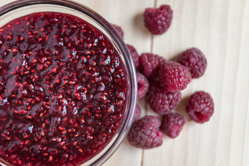 Homemade Raspberry jam in a glass bowl with fresh ripe organic Raspberries  on a wooden table