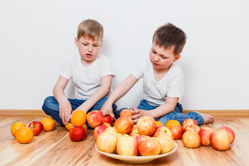 little children in white t-shirts and fruits on the floor