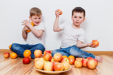 Fototapeta na wymiar little children in white t-shirts and fruits on the floor on white background