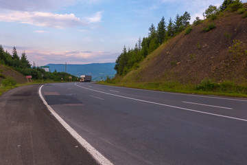 The route between the earthen hills along which a large long distance truck is traveling