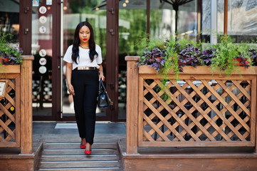 Stylish african american business woman with handbag on streets of city.