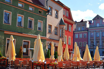 Outdoor cafe on sidewalk with empty tables and chairs with colorful plants and flowers in early summer morning in Poznan Poland.