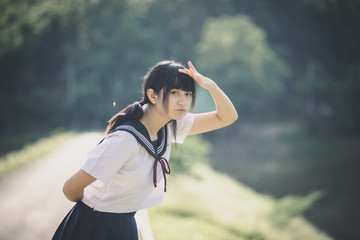 Naklejka premium Portrait of asian japanese school girl costume looking at park outdoor film vintage style