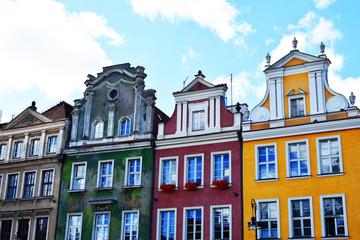 Fototapeta premium Four old town buildings with bright colorful decorative facades on blue sky background in summer morning in poznan poland.