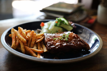 barbecued pork ribs steak with fresh vegetables on an old rustic wooden in restaurant