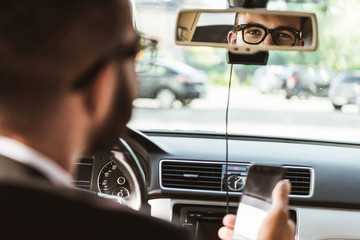 handsome driver looking at mirror in car